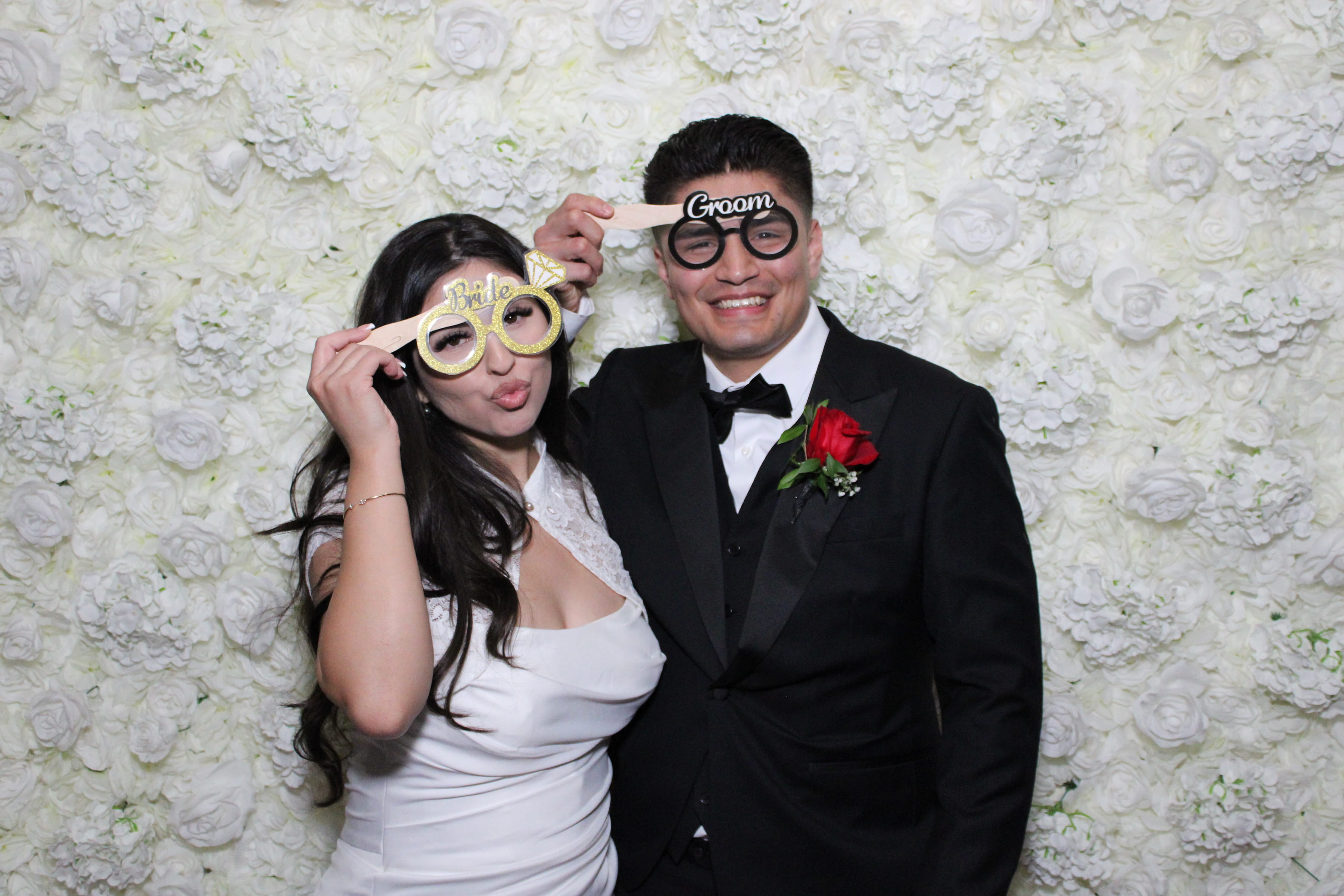 Wedding couple in soft tones against a white floral wall